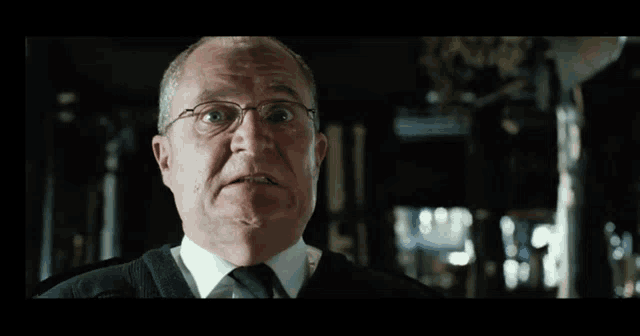 a man wearing glasses and a sweater is making a funny face .