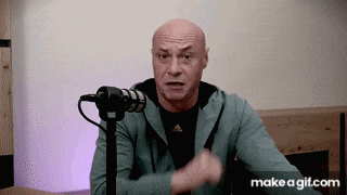 a bald man is talking into a microphone and making a funny face .