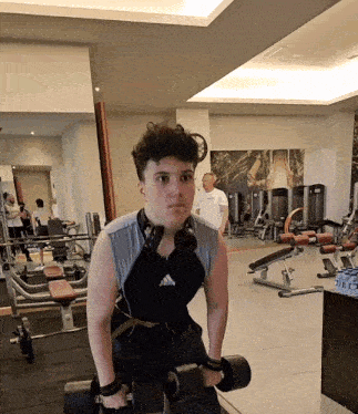 a man wearing headphones is lifting a dumbbell in a gym
