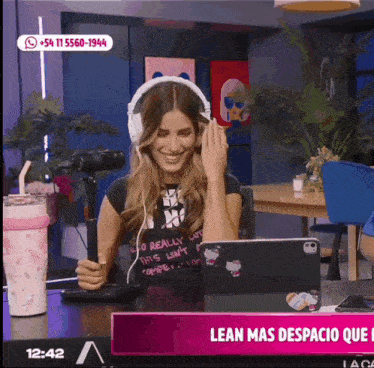 a woman wearing headphones is smiling in front of a laptop that says lean mas espacio que