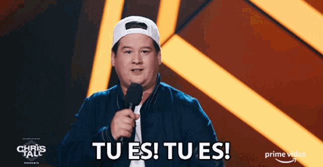a man holding a microphone in front of a sign that says tu es tu es