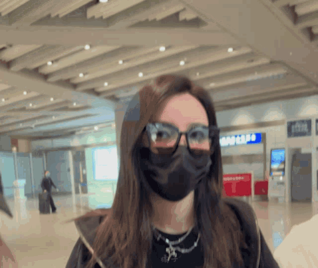 a woman wearing glasses and a mask stands in front of a samsung sign