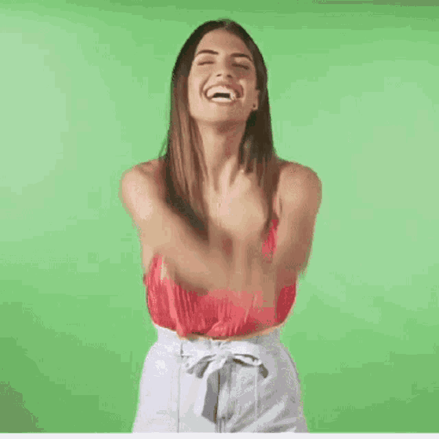 a woman in a red top is standing in front of a green screen with her hands on her head