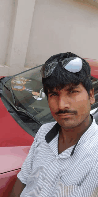 a man wearing sunglasses stands in front of a car
