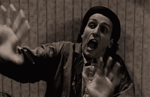 a man in a hat is making a funny face with his mouth open .