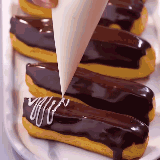 a pastry being decorated with chocolate icing and white frosting