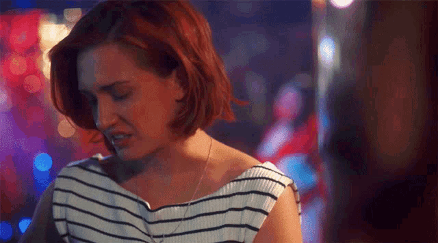 a woman with red hair is wearing a striped top and necklace .