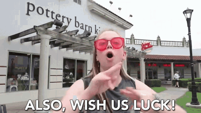a woman wearing red sunglasses says also wish us luck in front of a pottery barn store