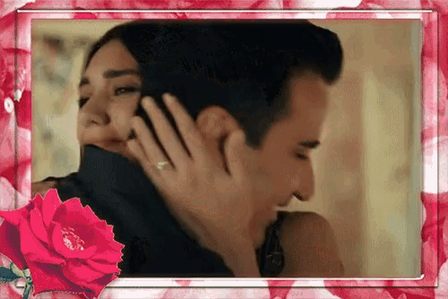 a picture of a man hugging a woman with a red rose in the foreground