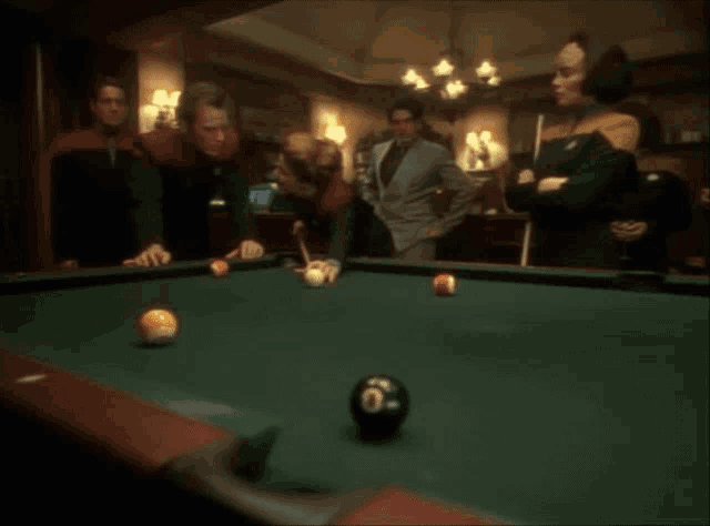 a group of people are playing pool together
