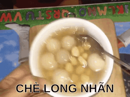 a person is holding a bowl of soup with the words che long nhan written on the side