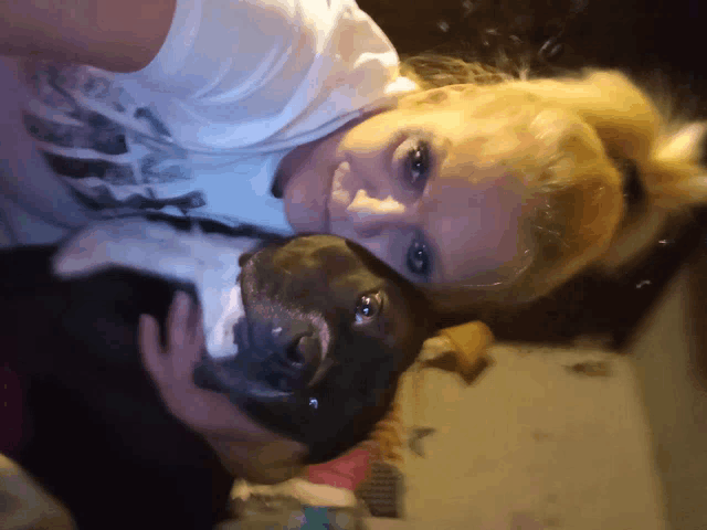 a woman in a white shirt holds a black dog