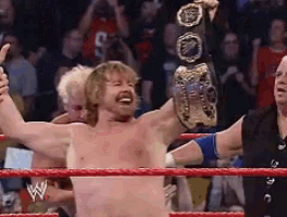a wrestler is giving a thumbs up while holding a belt in a wrestling ring