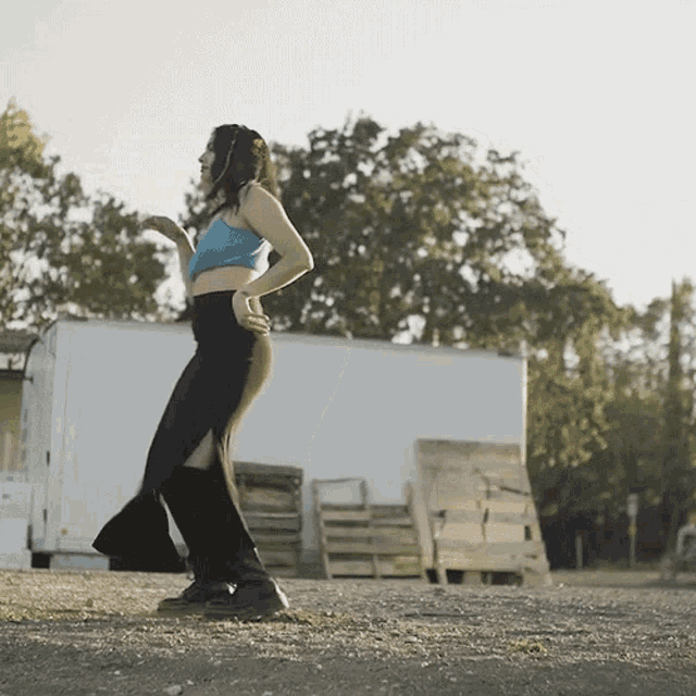 a woman in a blue crop top and black pants is dancing