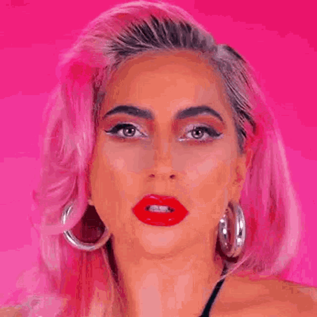 a close up of a woman 's face with pink hair and red lips on a pink background .
