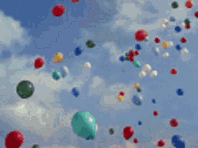 a bunch of colorful balloons are flying in the air