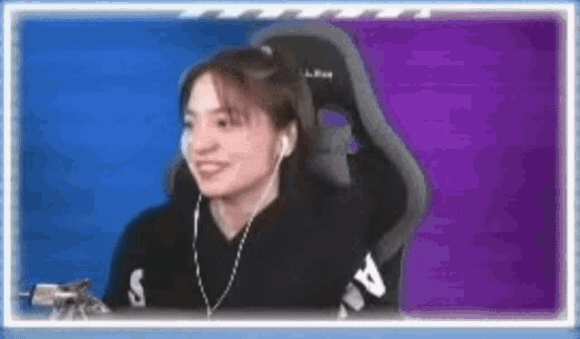 a woman is sitting in a chair with headphones on and smiling .