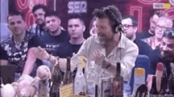 a group of people are sitting at a table with bottles of alcohol .