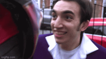 a man in a purple jacket and white shirt is smiling