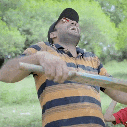 a man wearing sunglasses and a hat is holding a bat in his hands