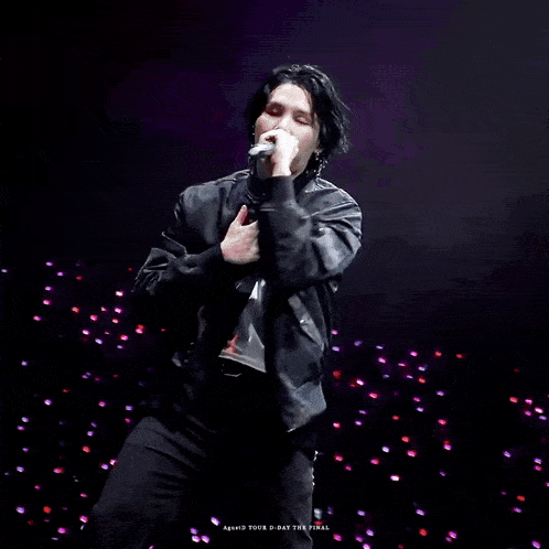 a man is singing into a microphone on stage .