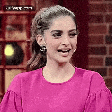 a woman in a pink top is smiling and laughing .