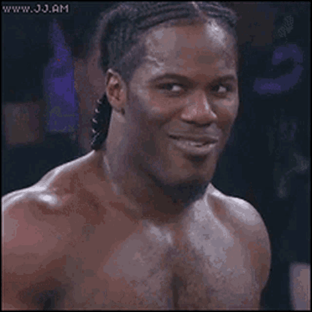 a shirtless man with braids on his hair is smiling .