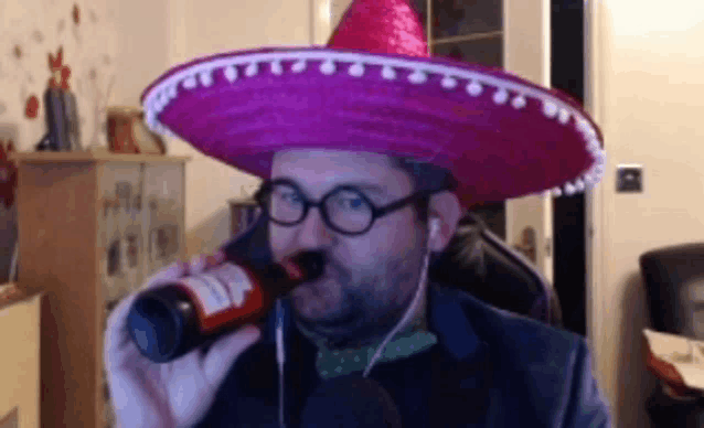 a man wearing a sombrero is drinking from a bottle of beer