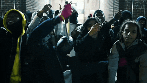 a group of people wearing masks and hoodies are standing in a dark room