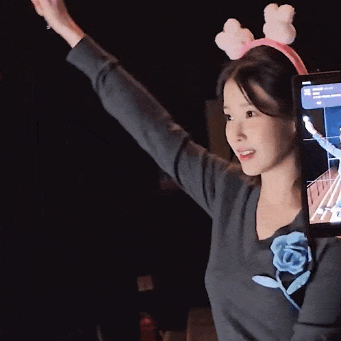 a woman wearing a headband with bunny ears is holding a tablet