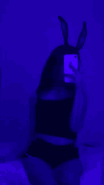 a person is taking a selfie in a dark room with a purple light .