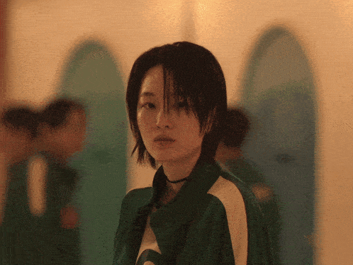 a woman with short hair is wearing a green jacket with the letter o on it