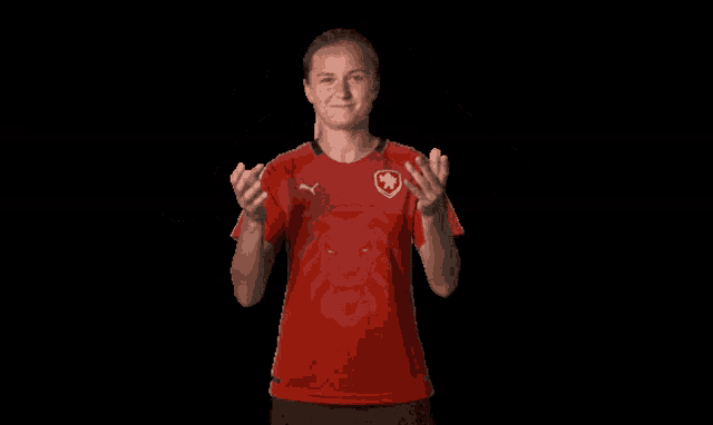 a woman in a red shirt with a lion on it holds her hands up