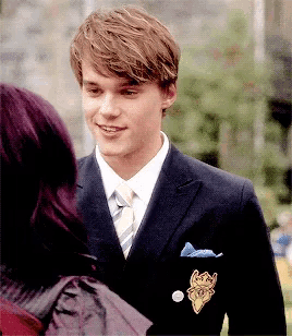 a young man in a suit and tie is smiling and looking at a woman