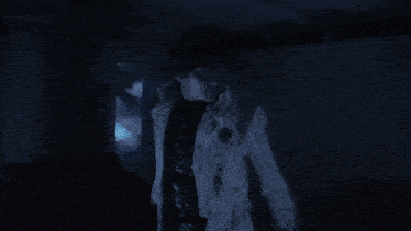a man in a white coat is standing in the dark