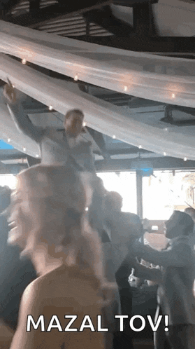 a group of people are dancing in a room with a man standing on a woman 's head .