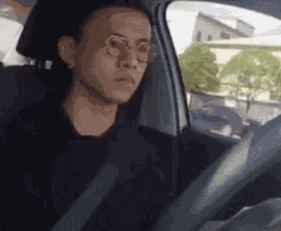 a man wearing glasses is sitting in a car .