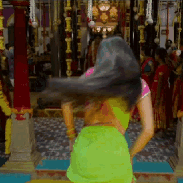 a woman in a green saree is dancing in front of a crowd