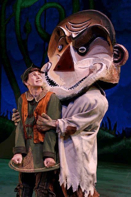 a man in a green vest stands next to a man in a monkey mask