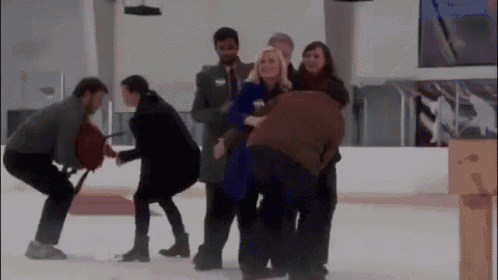 a group of people are standing on a ice rink and one of them is wearing a blue jacket