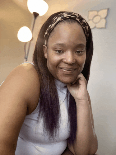 a woman wearing a headband and a white tank top smiles