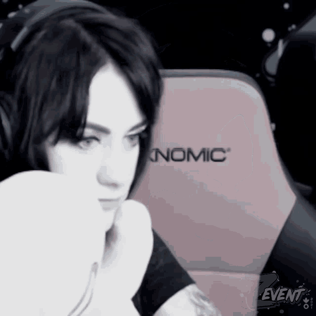 a woman wearing headphones sits in a pink nomic gaming chair