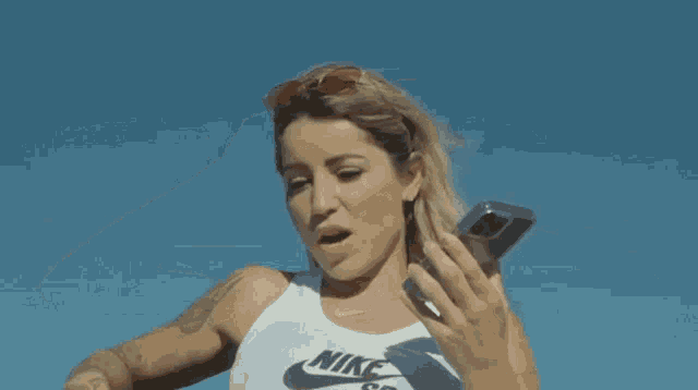 a woman with a tattoo on her arm is holding a cell phone and says that 's what i like to hear awesome