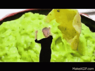 a woman is standing in front of a bowl of guacamole