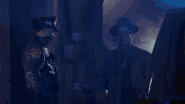 a man wearing a hat and a trench coat is standing next to a police officer