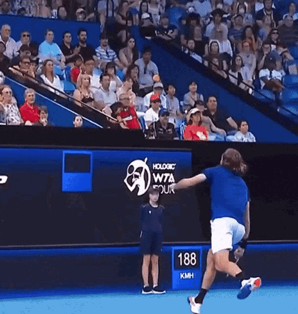 a man in a blue shirt is playing tennis in front of a crowd at a wta tour event