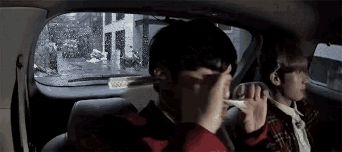 a man is sitting in the back seat of a car holding a thermometer in his hand .