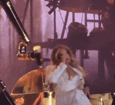 a woman in a white dress singing into a microphone on a stage