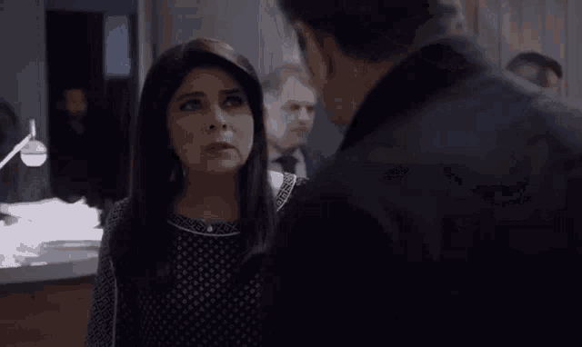 a man and a woman are standing next to each other in a room and talking to each other .