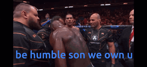 a man stands in front of a crowd with the words be humble son we own u